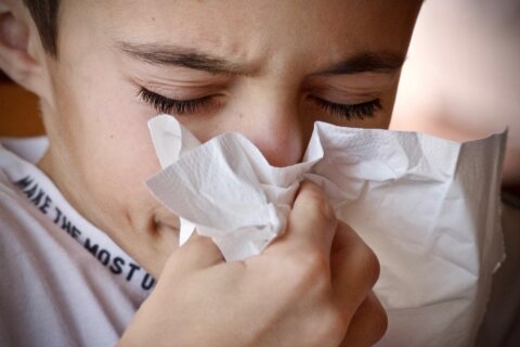Young person blowing their nose into a hankerchief