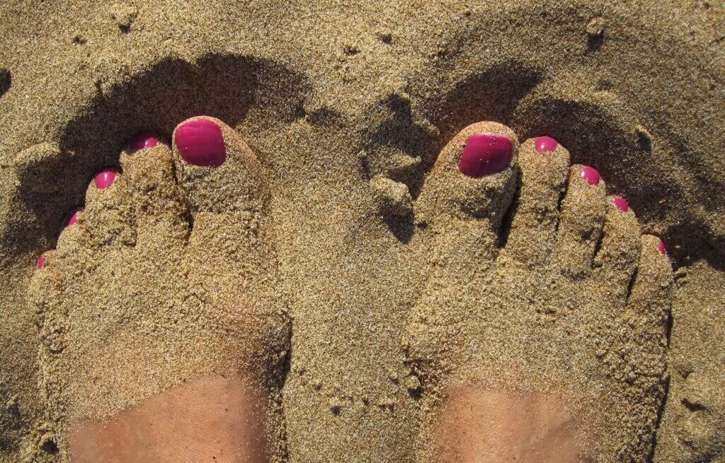 Woman's Feet in sand with painted toenails