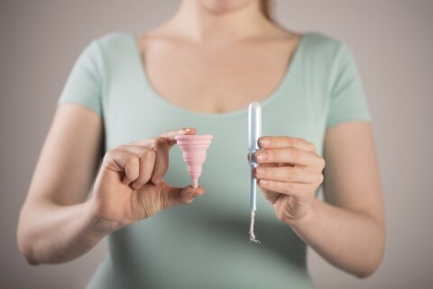 Woman holding a tampon and a menstrual cup