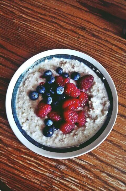 A photo of a bowl of porridge topped with blueberries and strawberries.