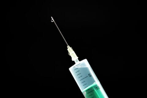 Photo of the tip of a vaccination needle on a black background.