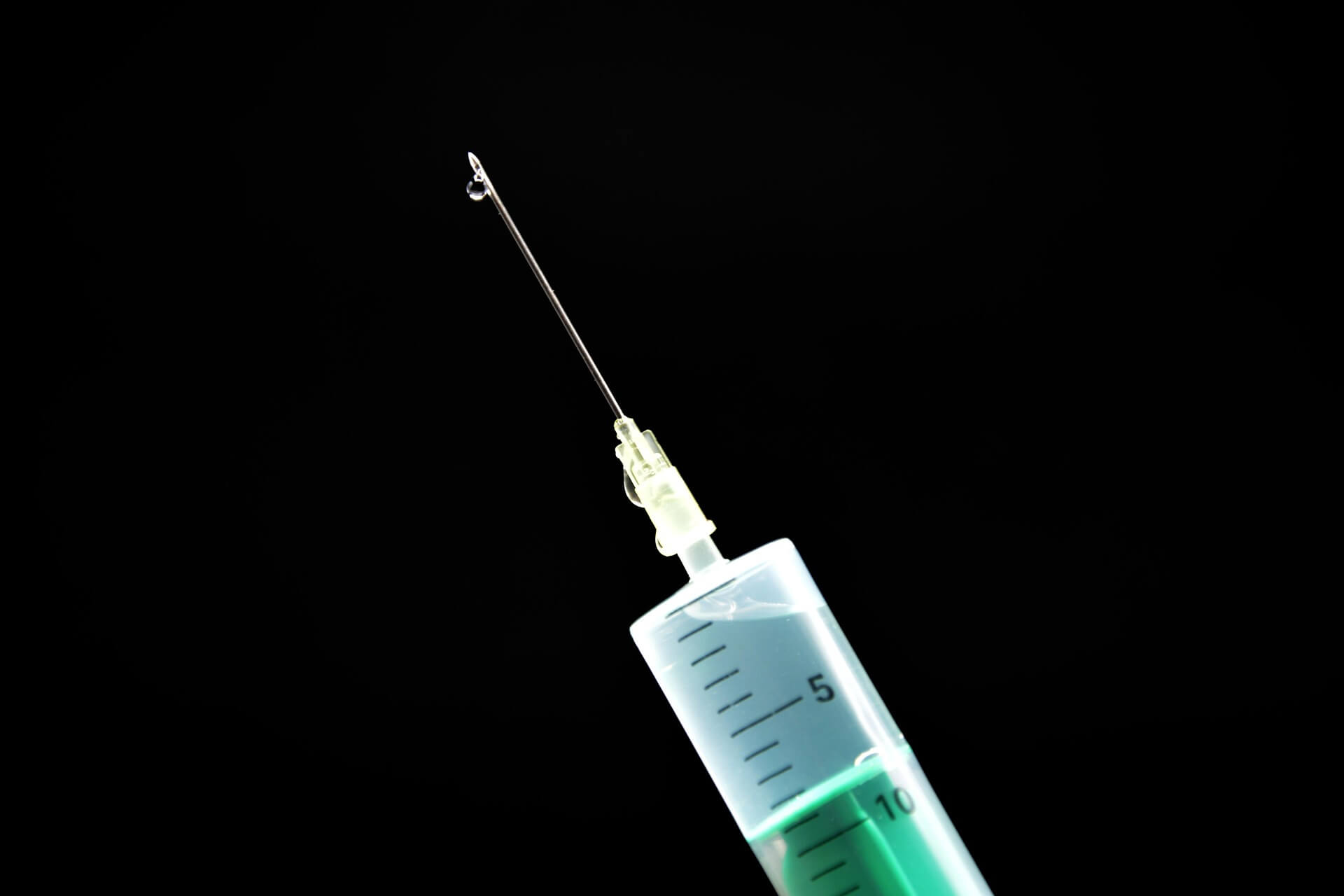 Photo of the tip of a vaccination needle on a black background.