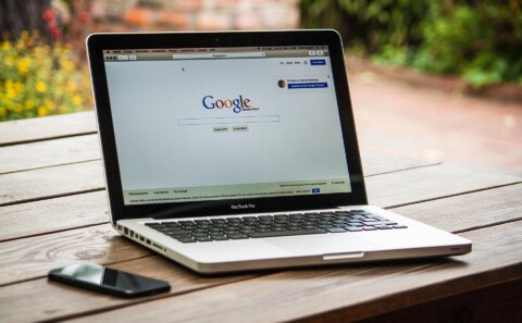 Open MacBook displaying the Google search page on a table.