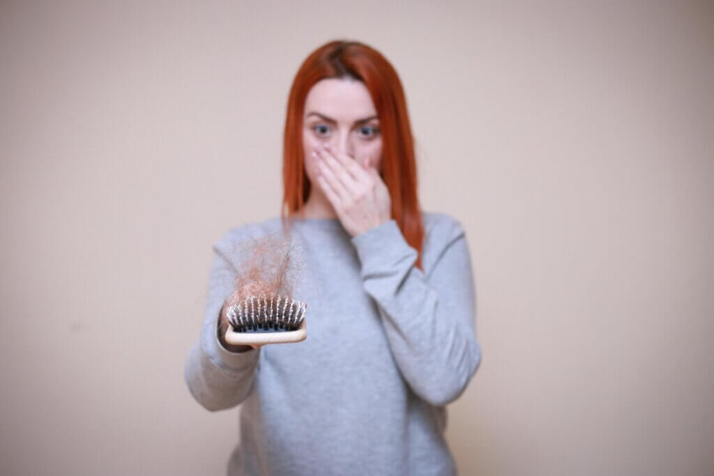 Woman examining hair loss in a hairbrush, a side effect some experience with weight loss injections