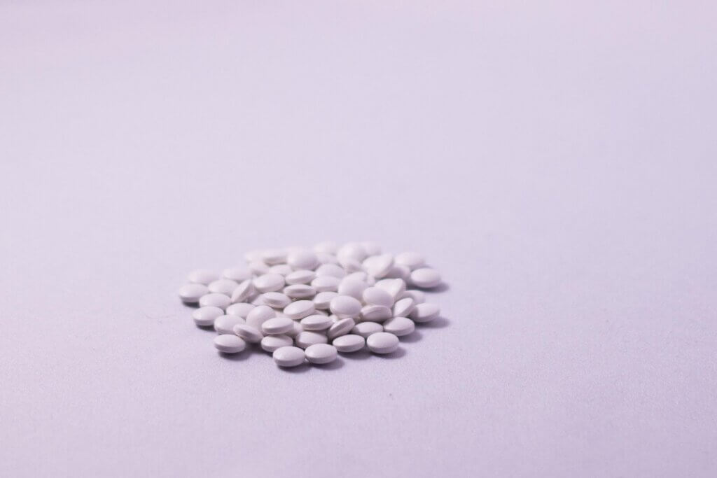 A small pile of white tablets on a pale pink surface. Morning-after pills